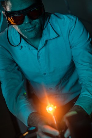 Rice University postdoctoral researcher Sean Collins adjusts a laser during experiments to take data from plasmonic nanoparticles. Photo by Jeff Fitlow