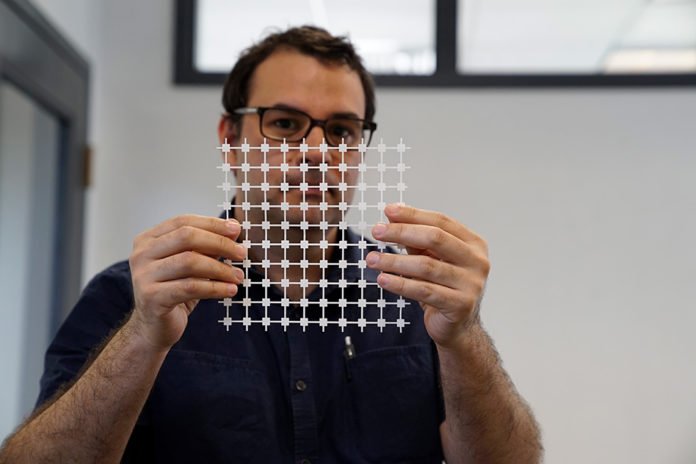 Jose Gomez-Marquez, co-director of MIT’s Little Devices Lab, holds a sheet of paper diagnostic blocks, which can be easily printed and then combined in various ways to create customized diagnostic devices.
