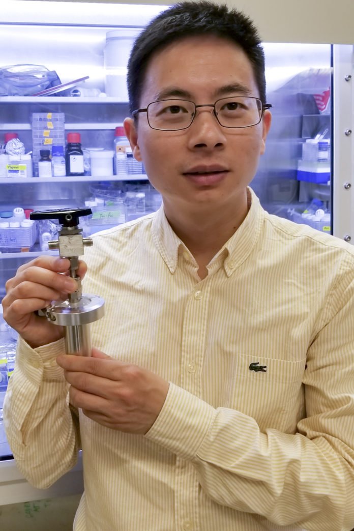 Postdoctoral scholar Wei Chen holds a prototype of what could one day be a ginormous battery designed to store solar and wind energy thanks to a water-based chemical reaction developed in the lab of Stanford materials scientist Yi Cui. (Image credit: Jinwei Xu)
