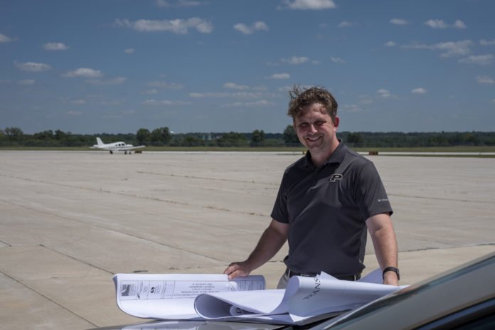 Adam Baxmeyer, Purdue University Airport manager of operations, reviews plans near the airport runway. Purdue is one of the few smaller airports with a traffic control tower. A Purdue-developed technology launched by Bluemac Analytics can help airports improve operations data collection. (Photo by Oren Darling, Purdue Research Foundation)