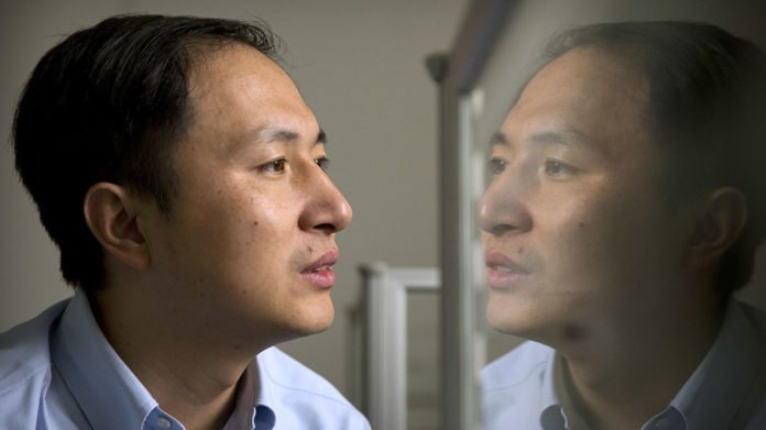In this Oct. 10, 2018 photo, He Jiankui is reflected in a glass panel as he works at a computer at a laboratory in Shenzhen in southern China's Guangdong province. Chinese scientist He claims he helped make world's first genetically edited babies: twin girls whose DNA he said he altered. He revealed it Monday, Nov. 26, in Hong Kong to one of the organizers of an international conference on gene editing. (AP Photo/Mark Schiefelbein)