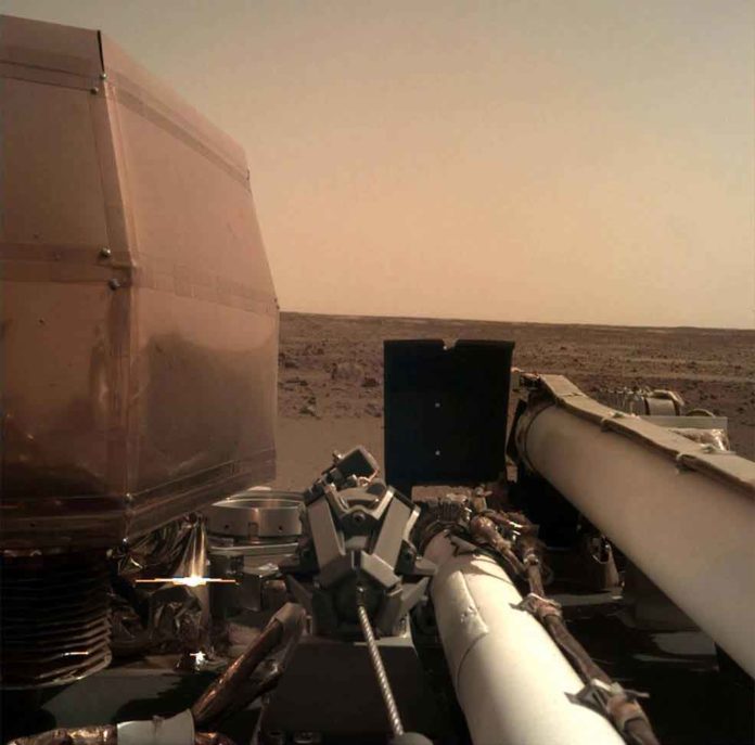 The Instrument Deployment Camera (IDC), located on the robotic arm of NASA's InSight lander, took this picture of the Martian surface on Nov. 26, 2018, the same day the spacecraft touched down on the Red Planet. The camera's transparent dust cover is still on in this image, to prevent particulates kicked up during landing from settling on the camera's lens. This image was relayed from InSight to Earth via NASA's Odyssey spacecraft, currently orbiting Mars. Credits: NASA/JPL-Caltech