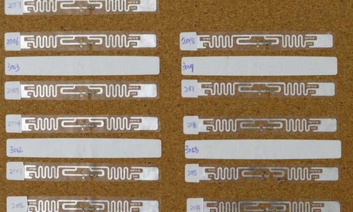 An RFID tag is modified by cutting out a small part its antenna (silver ribbon) and placing a small light-sensing phototransistor or temperature-responsive resistor (thermistor) on it. CREDIT University of Waterloo