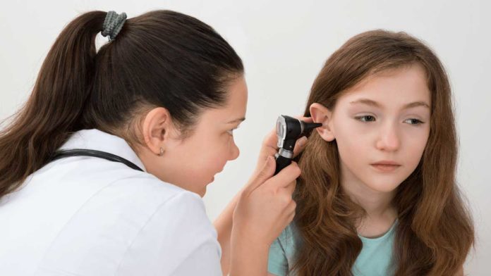 Female Doctor Examining Patient Ear With Otoscope In Clinic