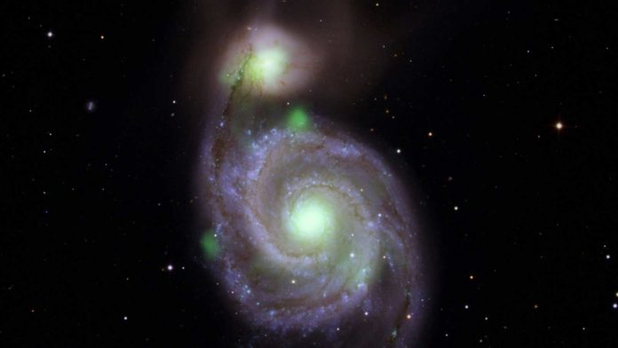 Bright green sources of high-energy X-ray light captured by NASA's NuSTAR mission are overlaid on an optical-light image of the Whirlpool galaxy (in the center of the image) and its companion galaxy, M51b (the bright greenish-white spot above the Whirlpool), taken by the Sloan Digital Sky Survey.Credit: NASA/JPL-Caltech, IPAC
