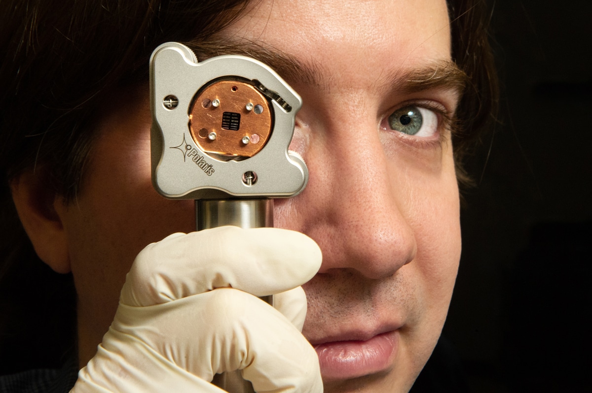 Thomas Corbitt looks through the custom-built device used to measure quantum radiation pressure noise. Credit: Elsa Hahne/LSU