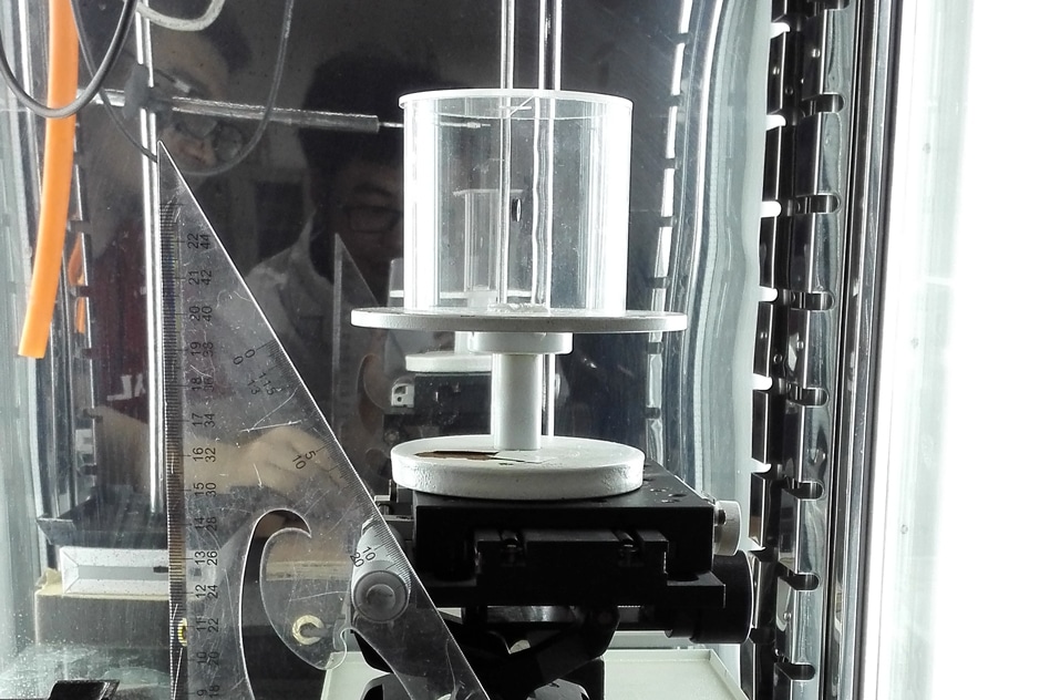The experimental setup used to study the behavior of spider dragline silk. The cylindrical chamber at center allowed for precise control of humidity while testing the contraction and twisting of the fiber. Photo courtesy of the researchers