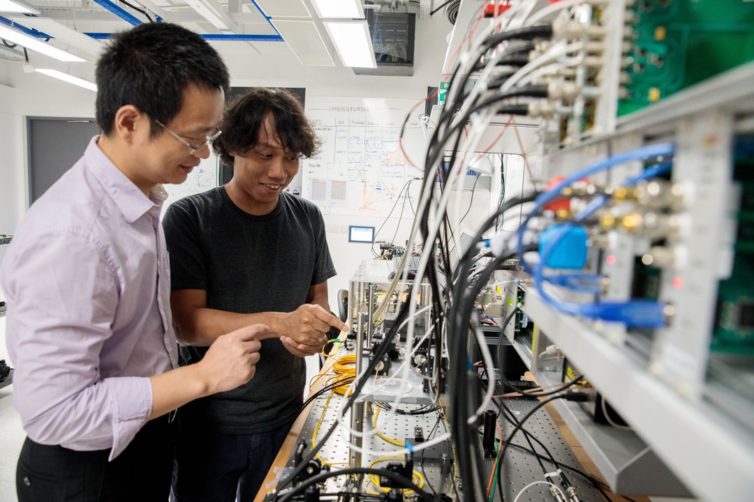 Jia Xu (pictured left) from Trustwave, Singtel’s cyber security subsidiary, and Soe Moe Thar (pictured right), a Research Assistant at the Centre for Quantum Technologies at the National University of Singapore (NUS) with some of the hardware being developed for advancing quantum technology at the NUS‐Singtel Cyber Security R&D Lab. (Credit: National University of Singapore)