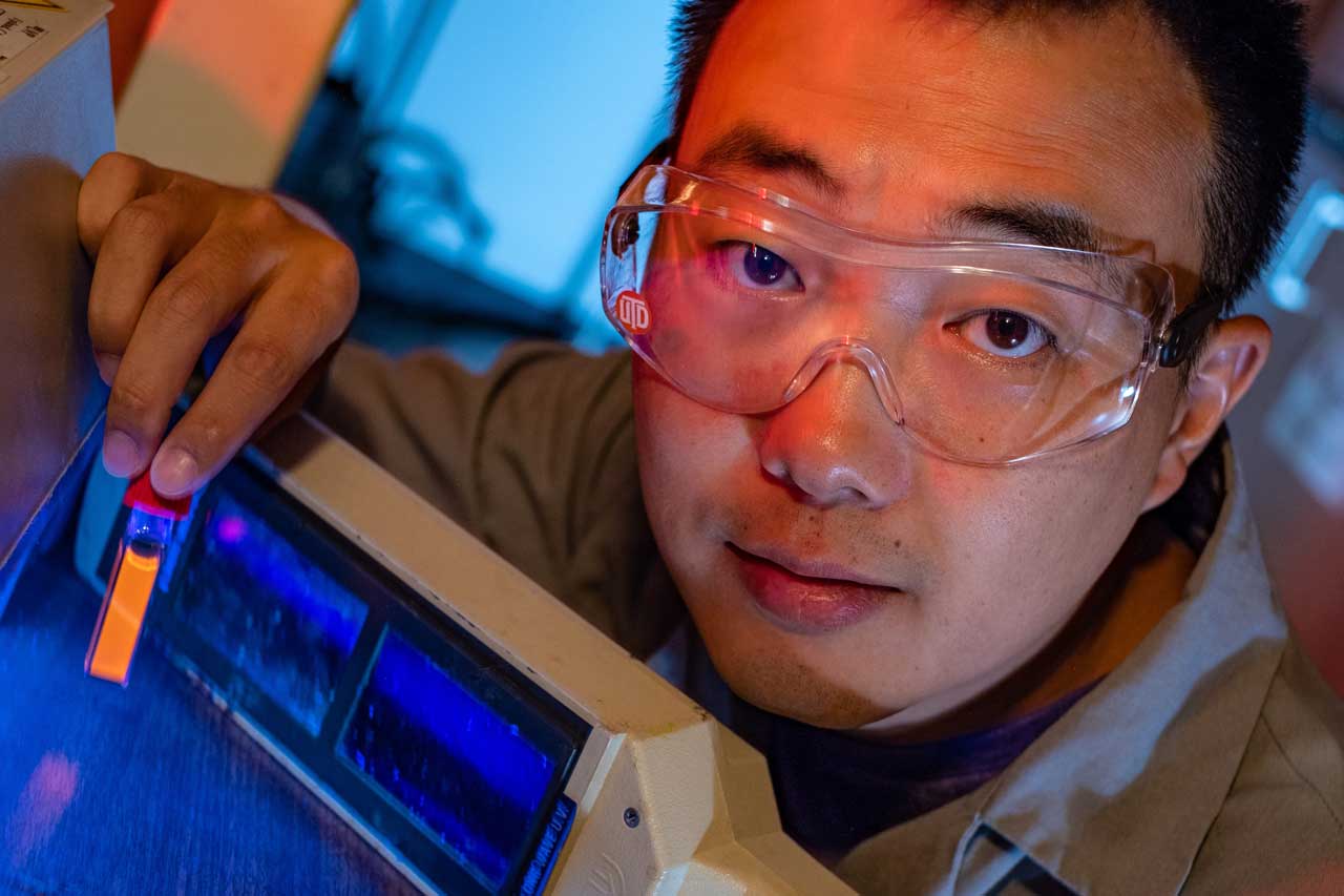 Rice graduate student Bo Jiang shows a fluorescing vial of soluble amyloid beta peptide aggregates implicated in the onset of Alzheimer’s disease. The peptides are tagged and tracked with a ruthenium complex developed at Rice that can monitor them in lab experiments as they grow over time. Photo by Jeff Fitlow