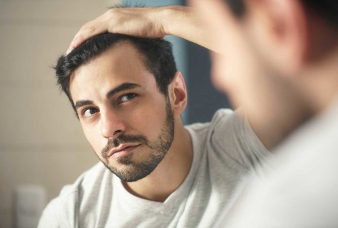 Man observing hair in mirror