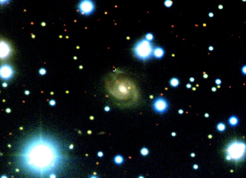 Image of SDSS J015800.28+654253.0, the host galaxy of Fast Radio Burst (FRB) 180916.J0158+65 (a.k.a. "R3") - acquired with the 8-metre Gemini-North telescope. Images acquired in SDSS g', r', and z' filters are used for the blue, green, and red colours, respectively. The position of the FRB in the spiral arm of the galaxy is marked by white cross hairs.  Image credit: Shriharsh Tendulkar / Gemini Observatory