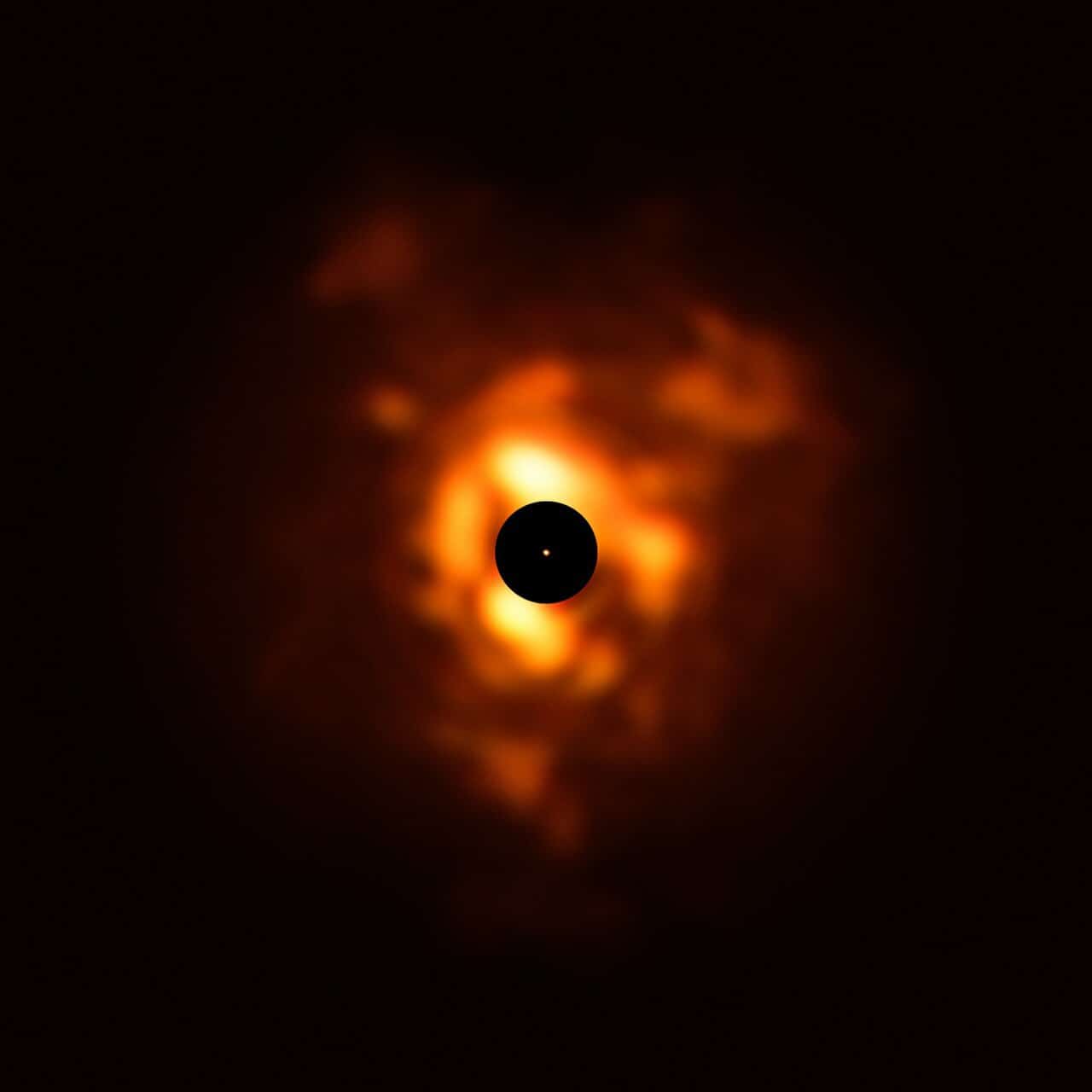 This image, obtained with the VISIR instrument on ESO’s Very Large Telescope, shows the infrared light being emitted by the dust surrounding Betelgeuse in December 2019. The clouds of dust, which resemble flames in this dramatic image, are formed when the star sheds its material back into space. The black disc obscures the star's centre and much of its surroundings, which are very bright and must be masked to allow the fainter dust plumes to be seen. The orange dot in the middle is the SPHERE image of Betelgeuse’s surface, which has a size close to that of Jupiter’s orbit. Credit: ESO/P. Kervella/M. Montargès et al., Acknowledgement: Eric Pantin
