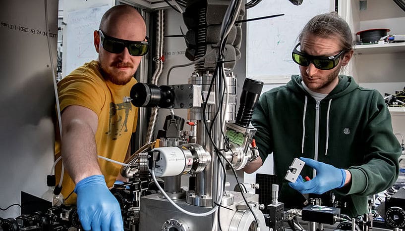 Scientists from Vienna, Kahan Dare (left) and Manuel Reisenbauer (right) working on the experiment that cooled a levitated nanoparticle to its motional quantum groundstate. (© Lorenzo Magrini, Yuriy Coroli/University of Vienna)