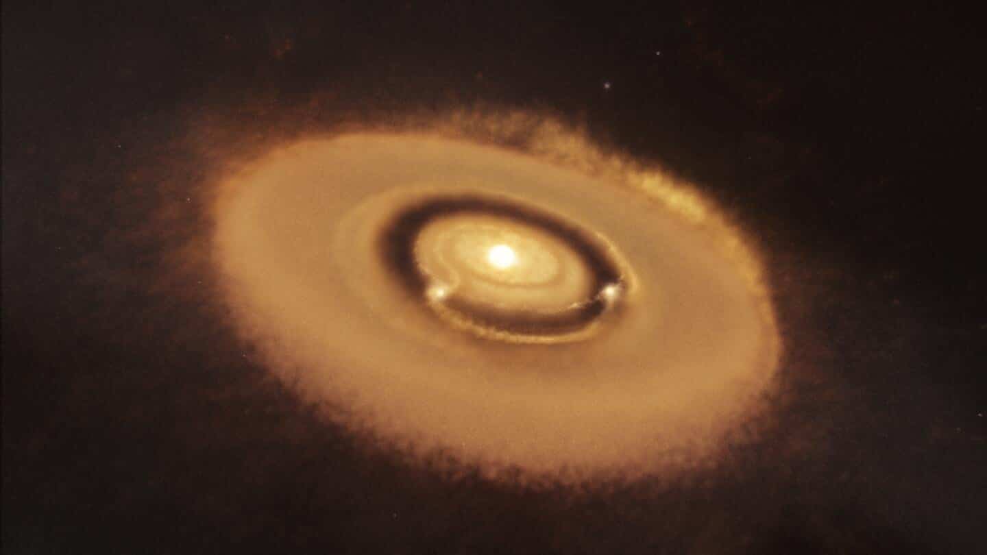 Artist’s impression of the PDS 70 system. The two planets are seen clearing a gap in the protoplanetary disk from which they were born. The planets are heated by infalling material that they are actively accreting and are glowing red. Note that the planets and star are not to scale and would be much smaller in size compared to their relative separations. Image Credit: W. M. Keck Observatory/Adam Makarenko