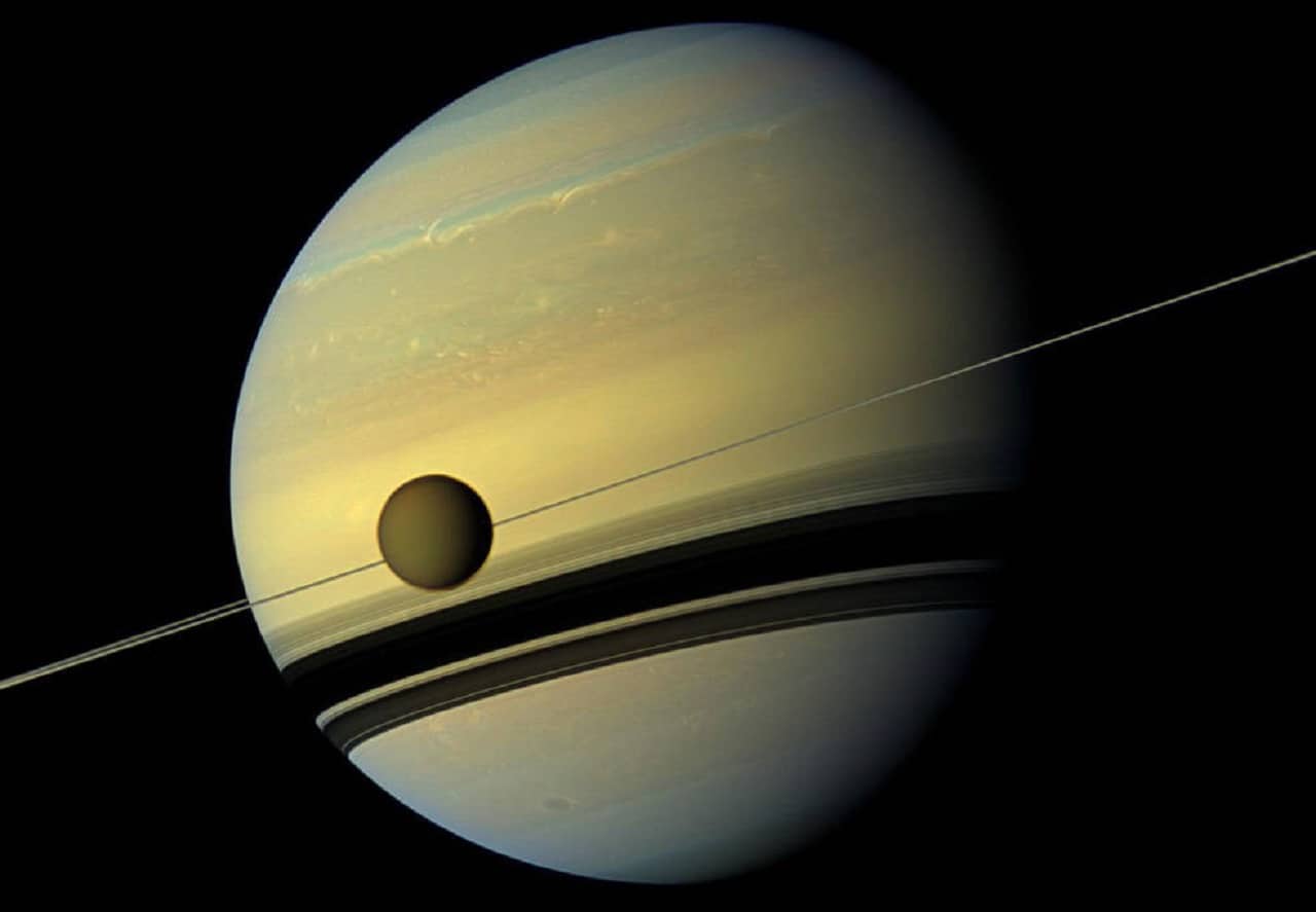 Larger than the planet Mercury, huge moon Titan is seen here as it orbits Saturn. Below Titan are the shadows cast by Saturn's rings. This natural color view was created by combining six images captured by NASA's Cassini spacecraft on May 6, 2012. Credits: NASA/JPL-Caltech/Space Science Institute