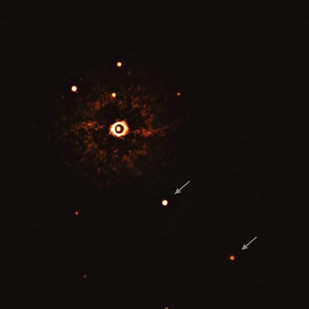 The image was captured by blocking the light from the young, Sun-like star (top-left of centre) using a coronagraph, which allows for the fainter planets to be detected. The bright and dark rings we see on the star’s image are optical artefacts. 