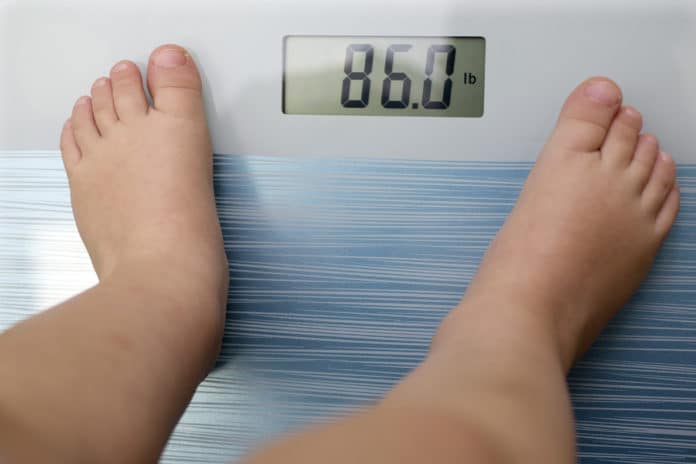 Children overweight, young boy on a bathroom scale,