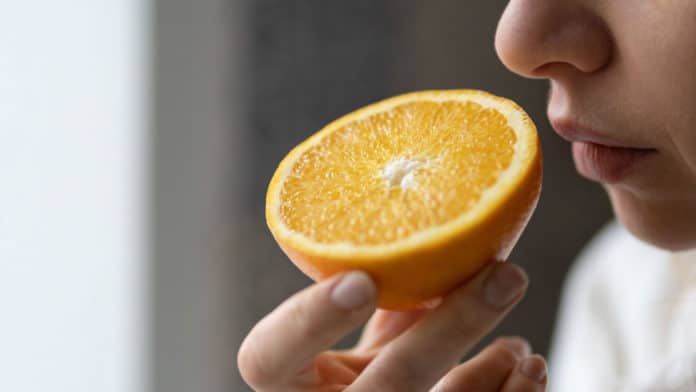 person smelling a slice of orange