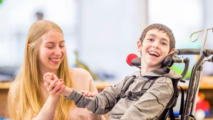 Image showing motor-impaired child laughing with caretaker beside