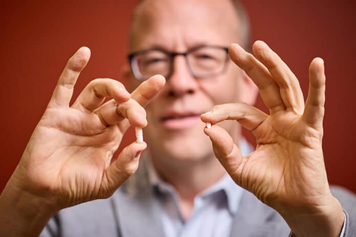 Eric J. Lenze, MD, holds an antidepressant drug in one hand and aripiprazole