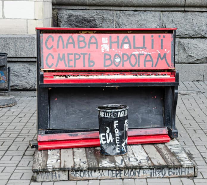 Piano in Kyiv, 2017. In Ukrainian above: ‘Glory to the nation. Death to the enemies.’ Below: ‘Peaceful meeting for winning the information war.’
