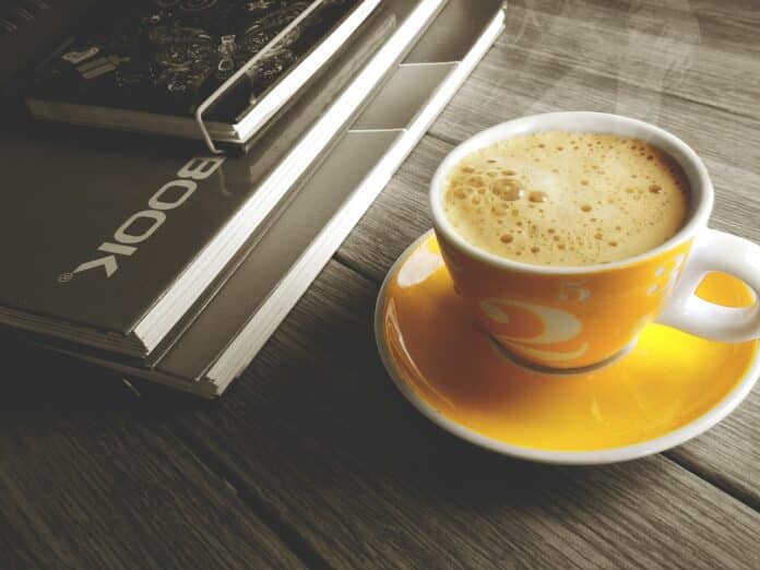 Image showing cup of coffee besides book