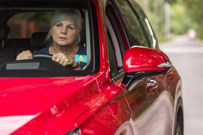 Old lady behind the wheel of a luxury red car