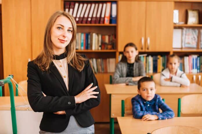Image showing school teacher on background of sitting at desk students.