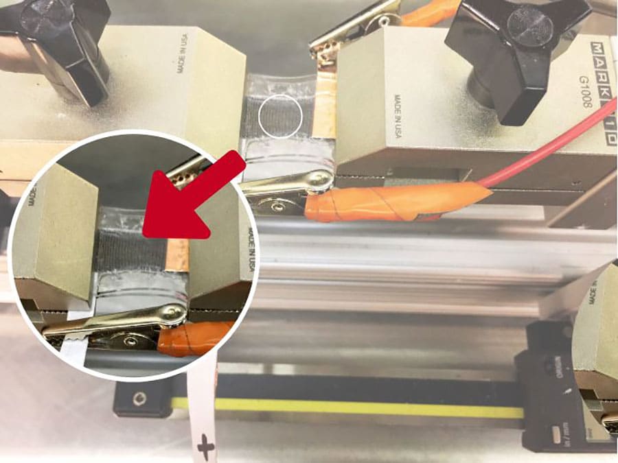 UH researchers stretching, testing and monitoring the stretchable fabric-based lithium-ion battery's performance. The gray striated section is the battery prototype.