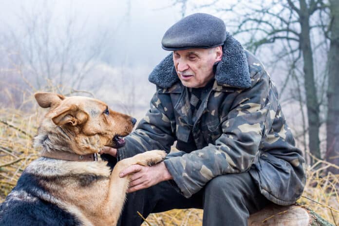 Image showing an elderly man on nature communicates with a dog.