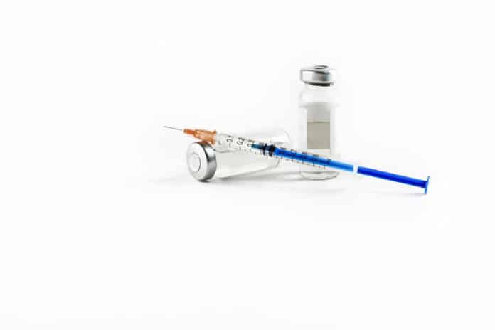 Glass vials with clear liquid with insulin syringe and injection needle isolated on white background