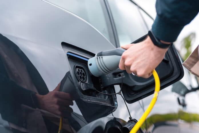 Image showing man plugging in charger into an electric car at charge station