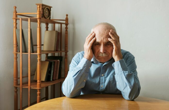 Worried elderly man with his head in his hands
