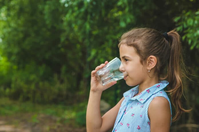 Child girl drinks water from a glass