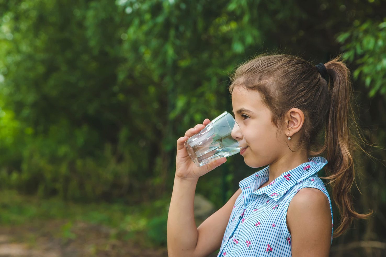 Child girl drinks water from a glass
