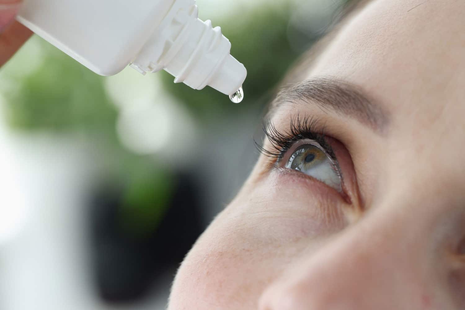 Woman dripping into her eyes with antibacterial drops closeup treatment of viral conjunctivitis