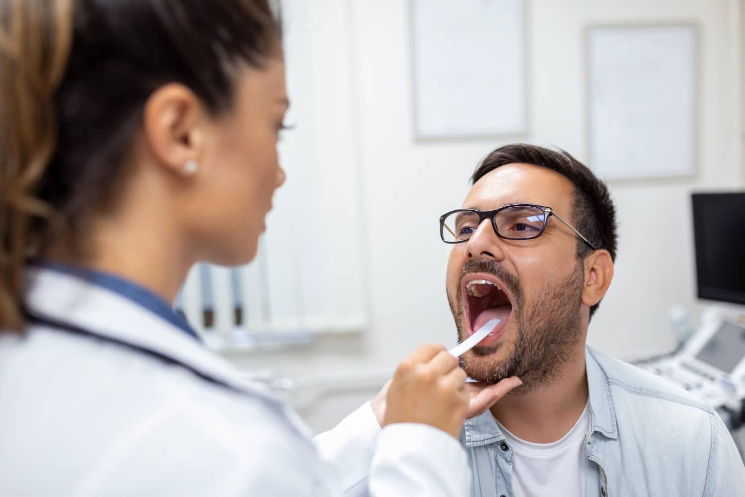 Male patient opening his mouth for the doctor to look at his throat