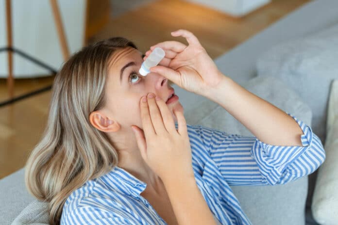 woman dropping eye lubricant to treat dry eye