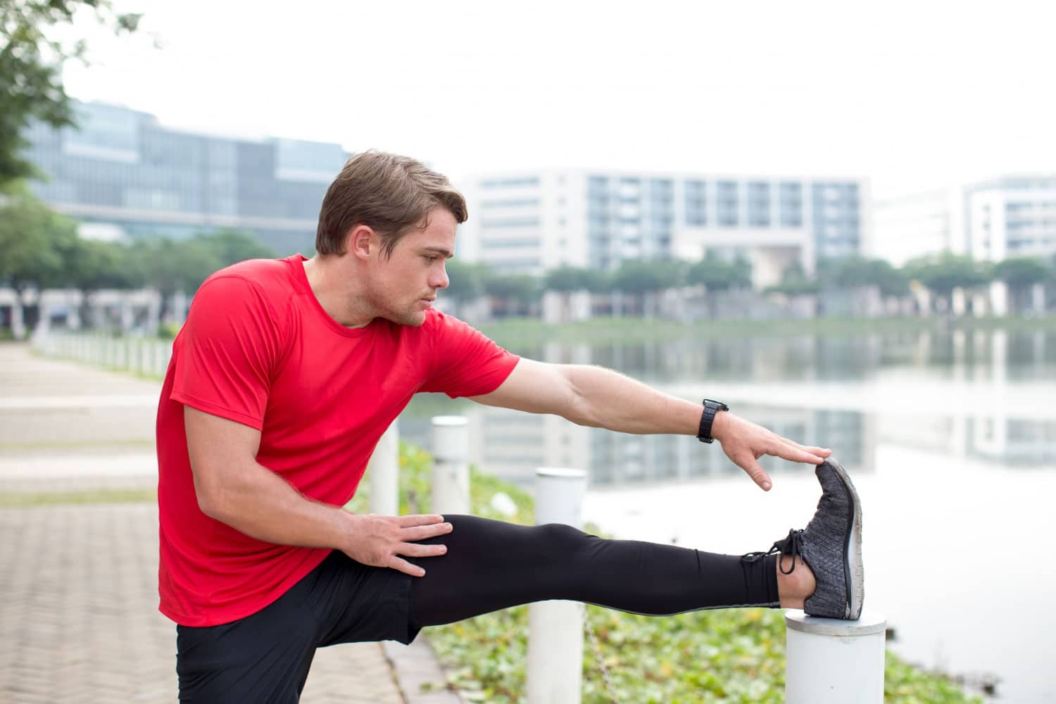 Serious sporty man stretching leg outdoors