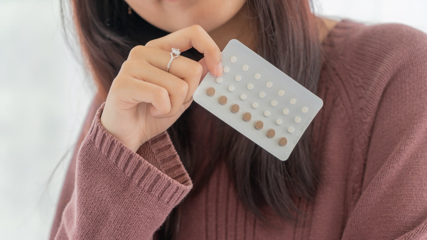 Beautiful asian women holding birth control pill