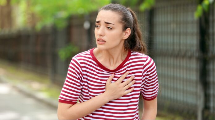 Young woman suffering from heart attack outdoors