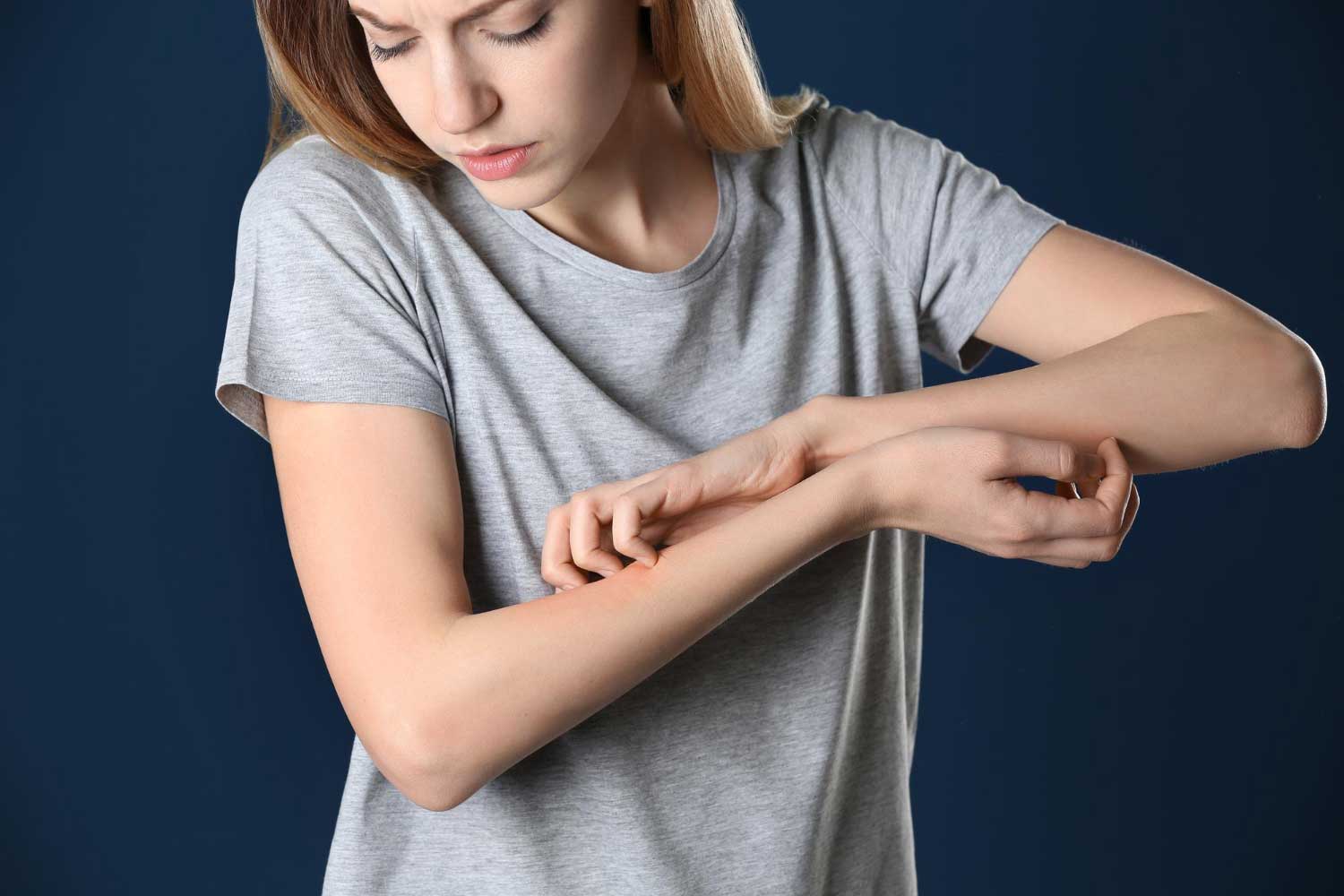 Woman scratching forearm on color background closeup allergy symptom