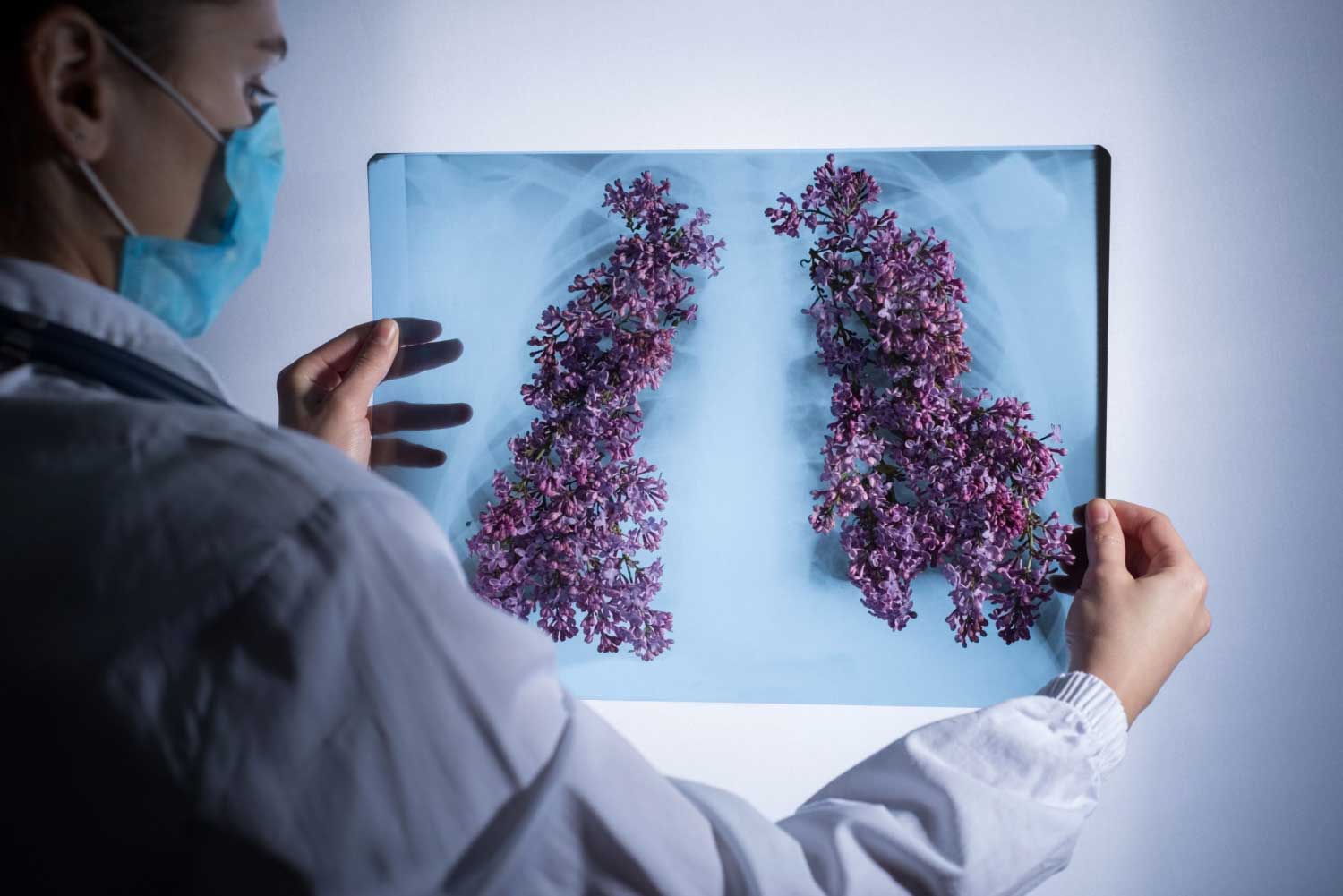 Doctor in a protective mask looks at a picture of the patients lungs