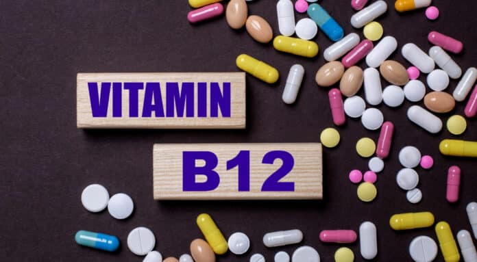 Vitamin b12 is written on wooden blocks near multi-colored pills. medical concept