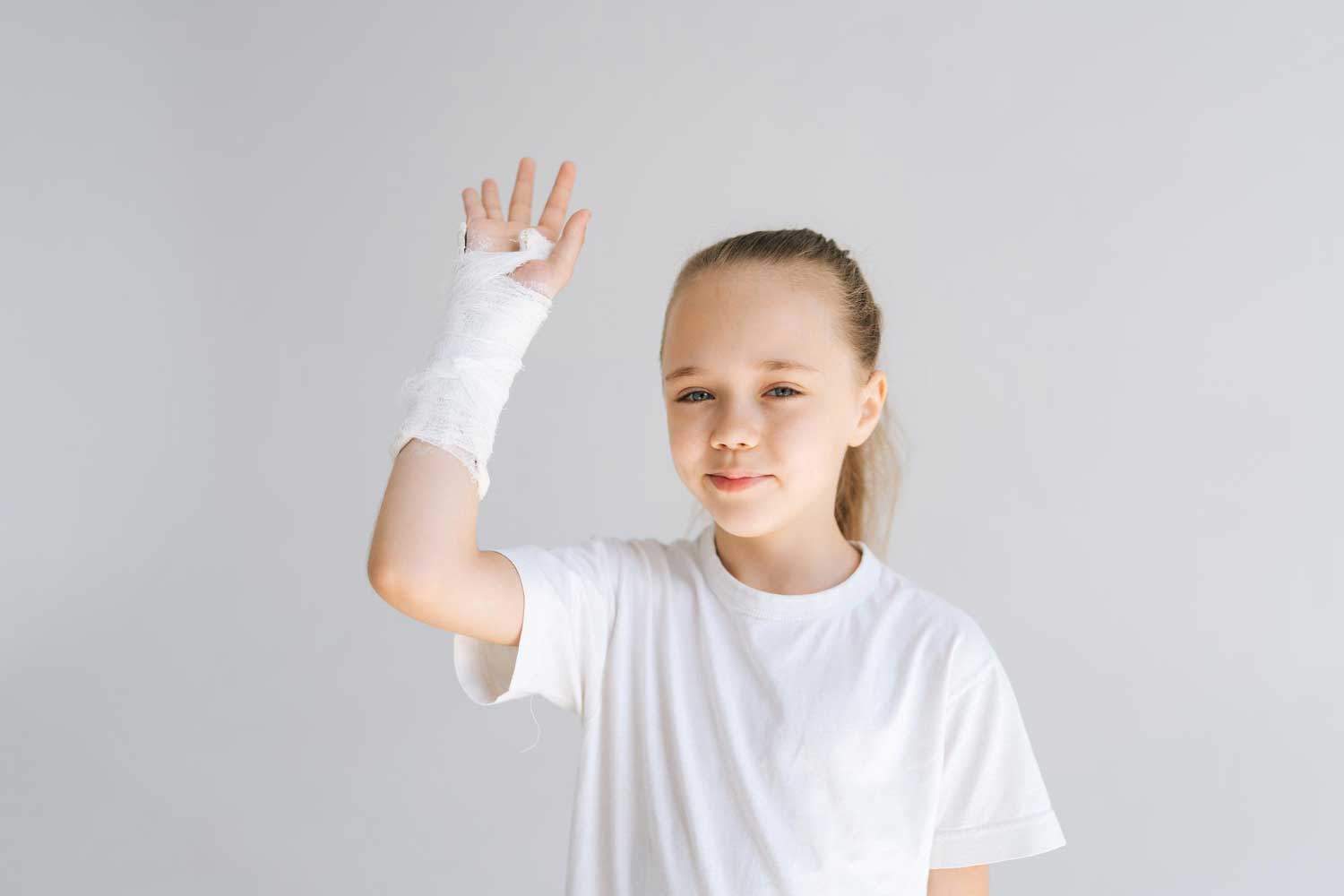 portrait of cheerful little girl with broken hand wrapped