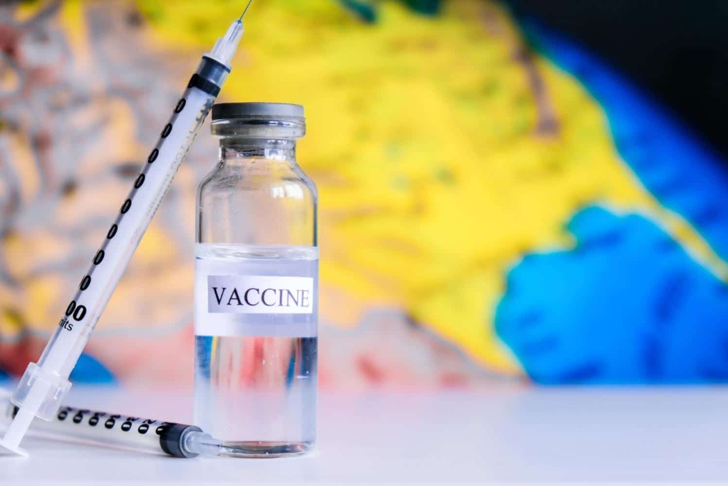 Photo syringe ampoules covid vaccine on a world map fight the coronavirus sarscov pandemic coronavirus.