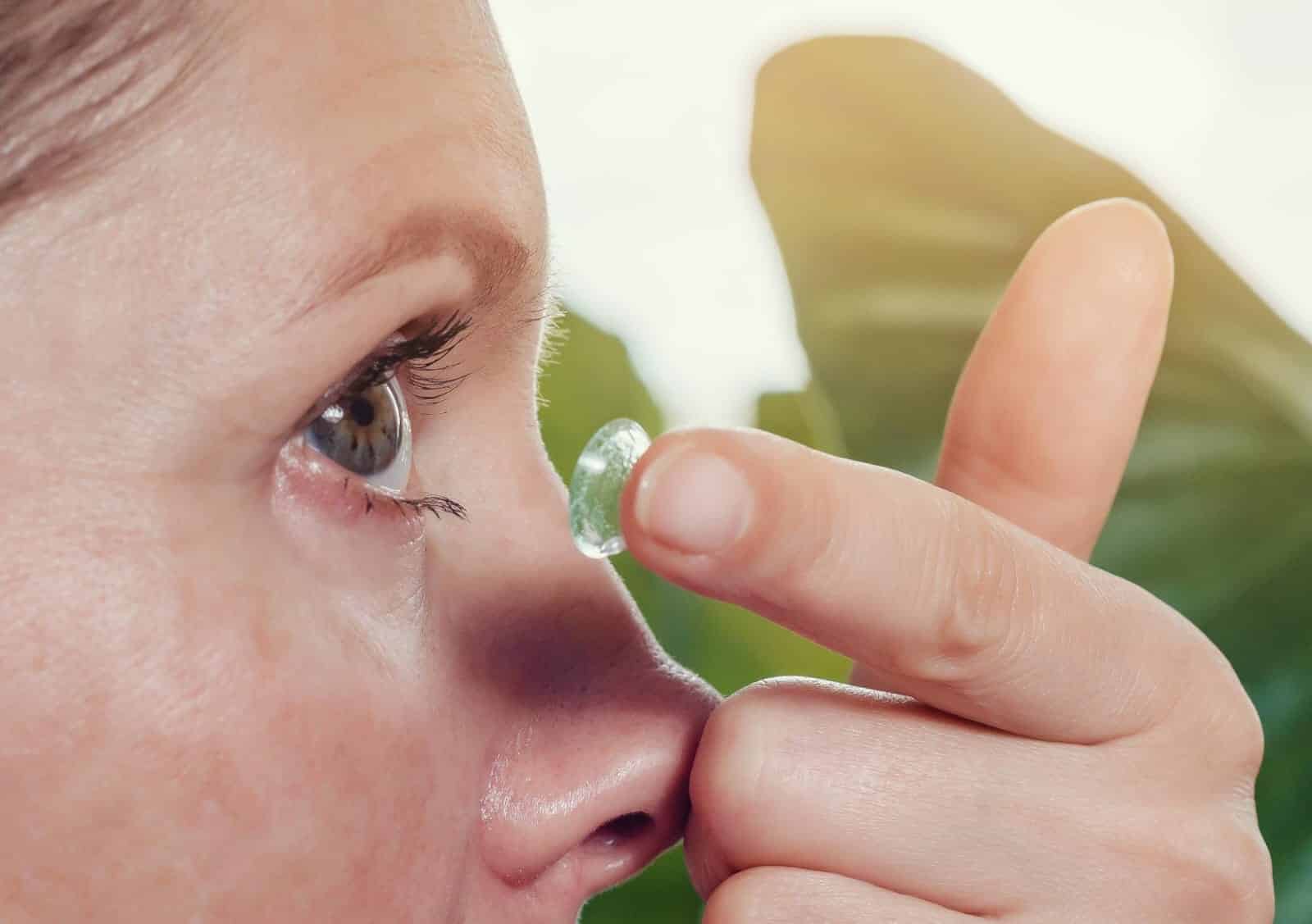 woman inserts a contact lens into the eye