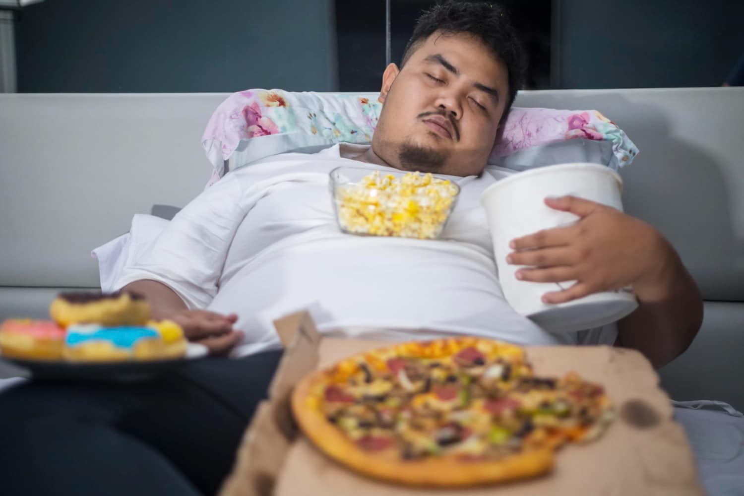 Asian obese man sleeping with junk foods