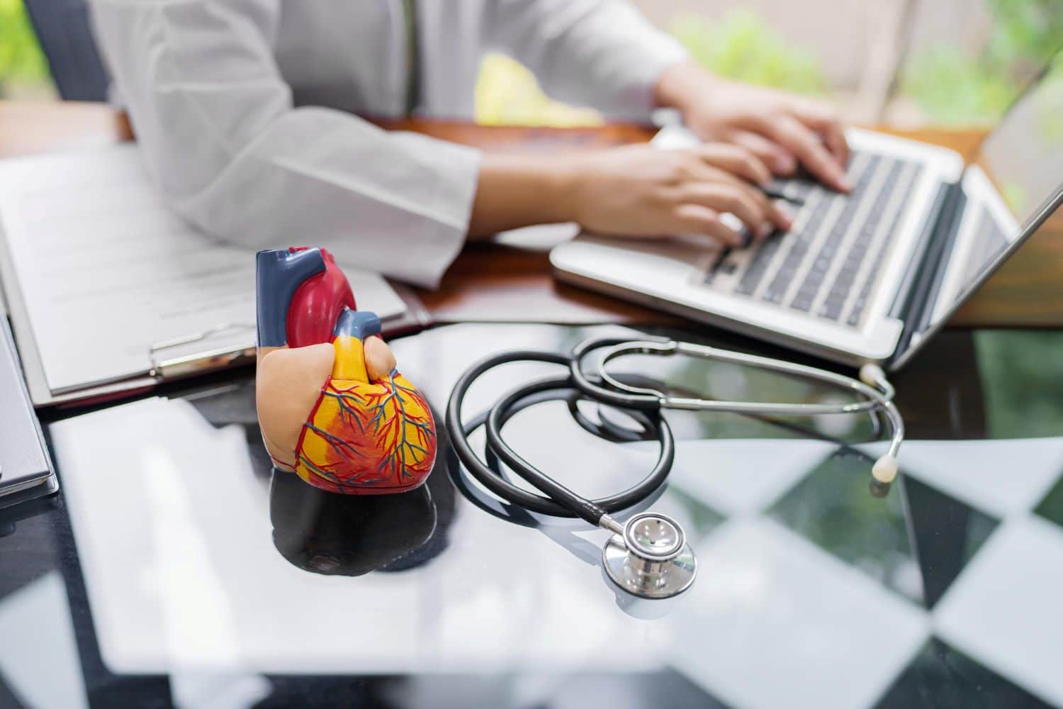 Doctor consult patient on laptop with anatomical model of human heart Cardiologist supports the heart Online doctor appointment